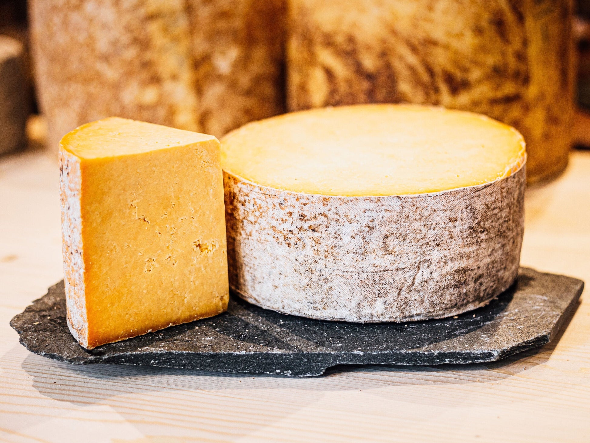 A deep rich orange clothbound cheese on a natural slate 