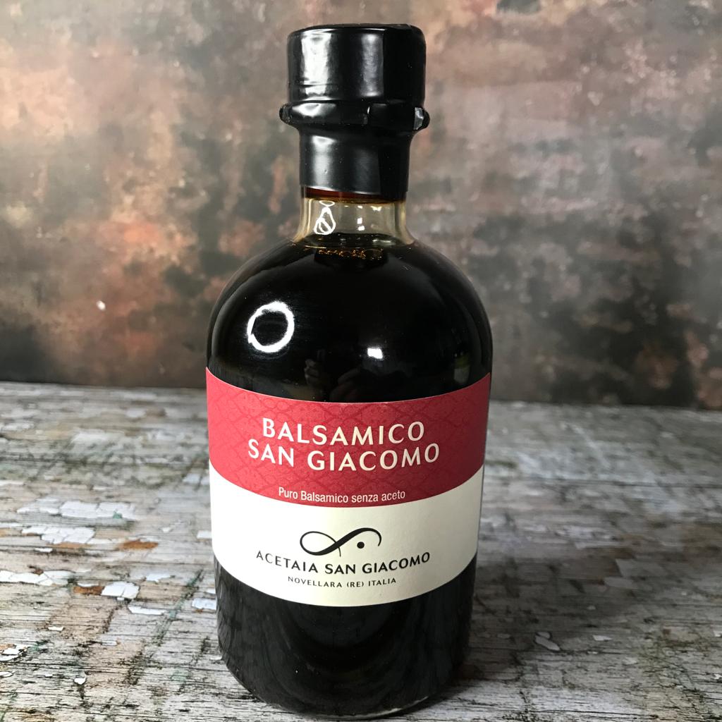 A bottle of rich balsamic vinegar, with traditional San Giocomo branding, red and white label and italian description: pure balsamic.